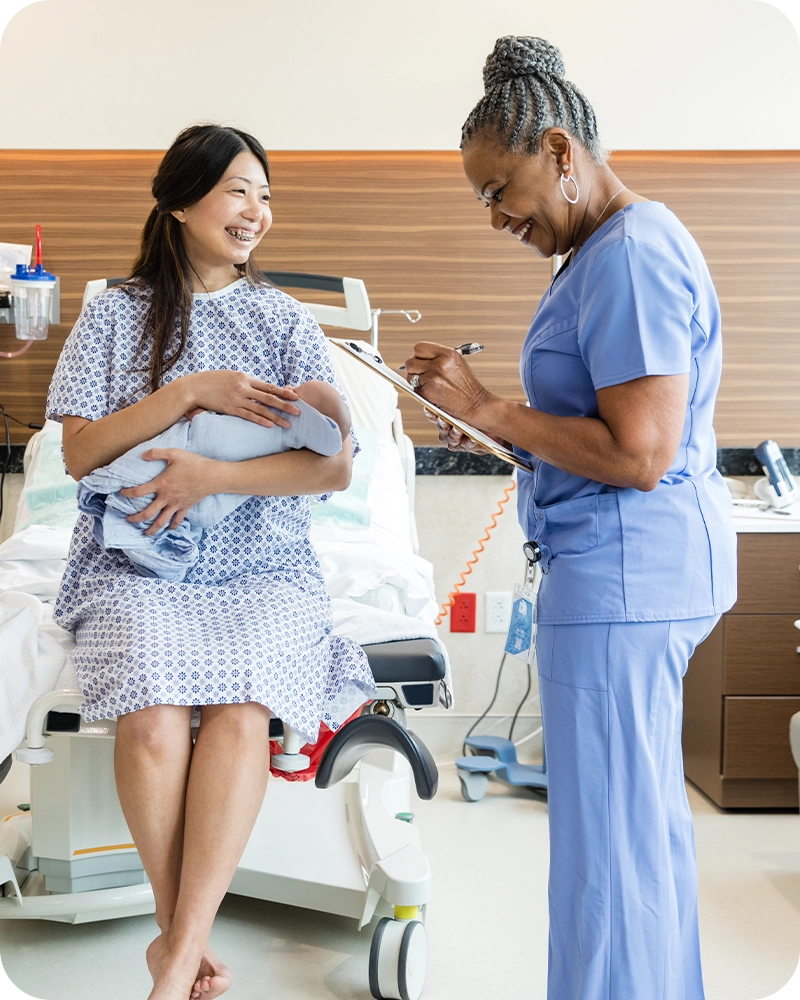 new mother with her infant filling out paperwork with a nurse